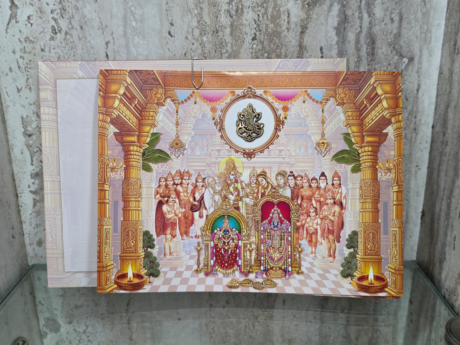 Luxury wedding invitation card featuring a golden Ganesha idol and grand Srinivasa Kalyanam in a pillared mandapam, blending royal tradition with modern elegance.
