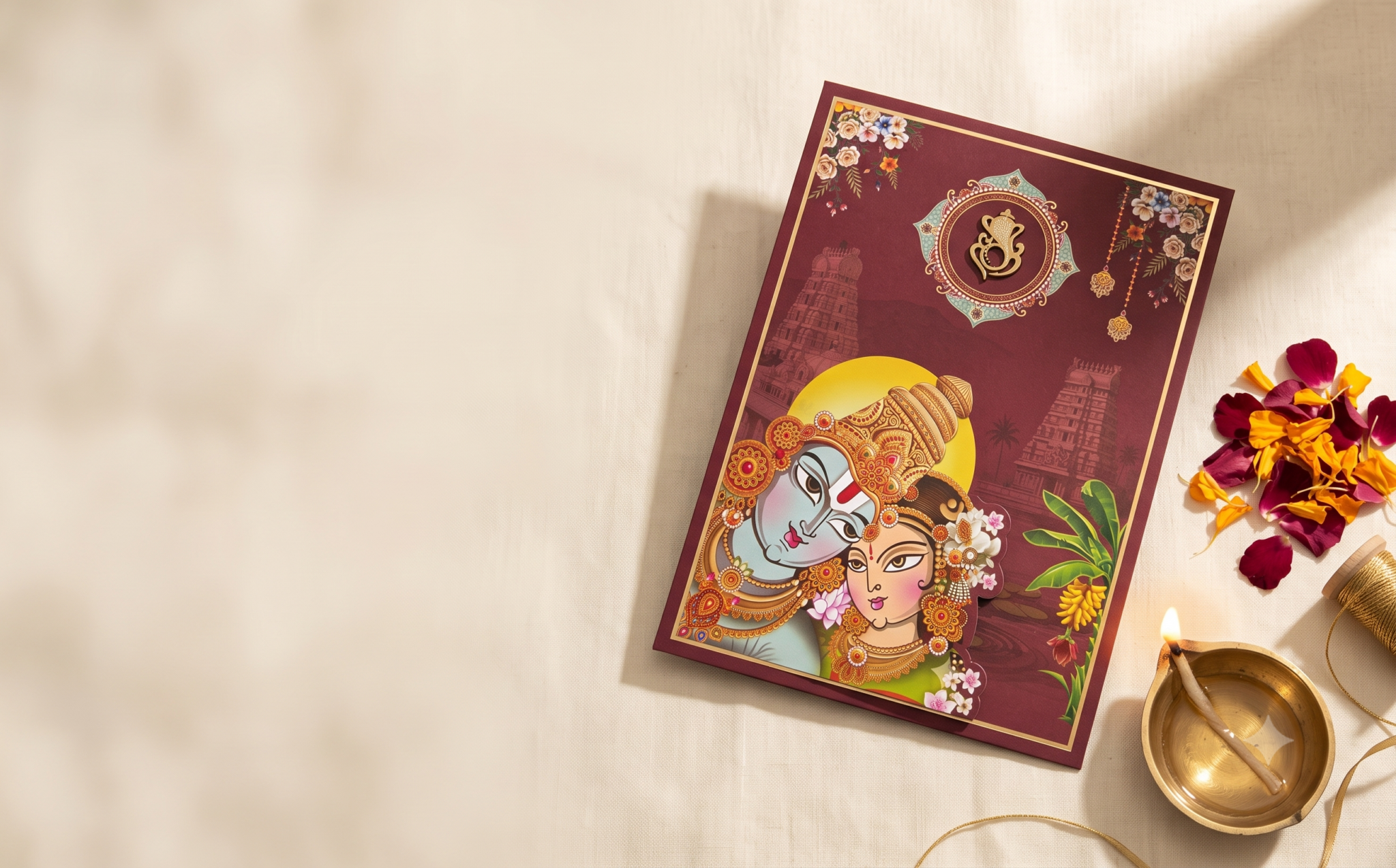 Kothapalli Cards Radha Krishna wedding invitation flatlay with marigold petals, gold thread and a lit brass diya